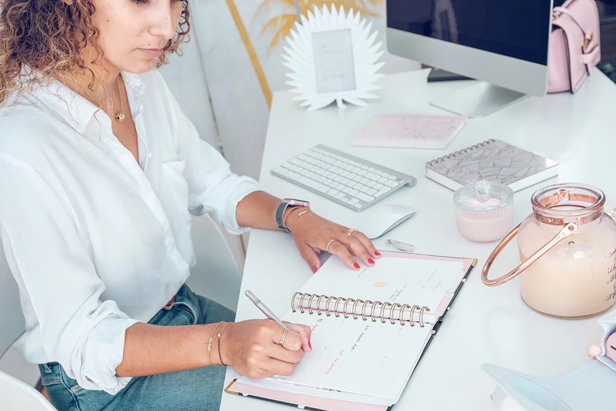 woman writing in daily planner for business