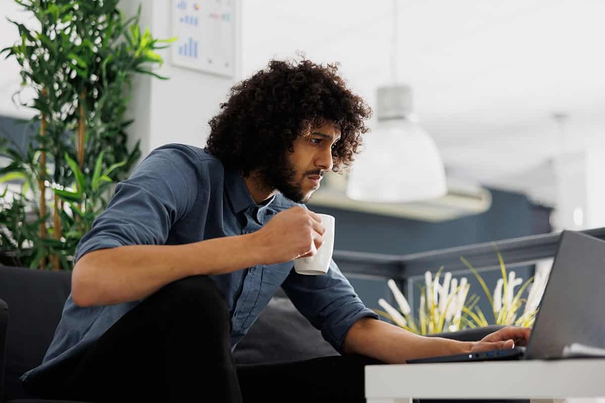 man working on his laptop at home drinking coffee